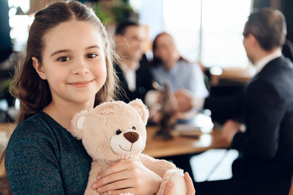 girl smiling holding a bear stuffed animal