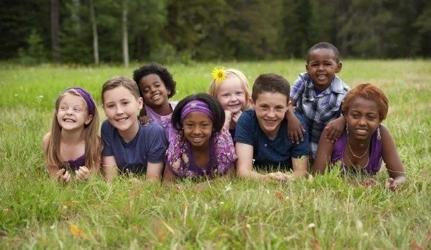 kids from different ethnicities smiling laying on the grass