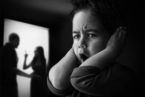 Young boy covering his ears to avoid hearing domestic violence