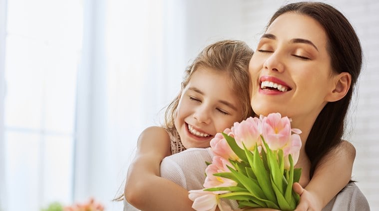 Mother and daughter hugging holding pink flowers