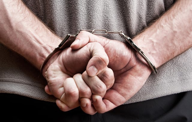 A man with his hands handcuffed behind his back