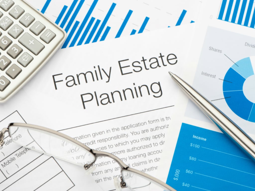 The image shows glasses, and pen and a calculator accompanied by Estate Planning documents.