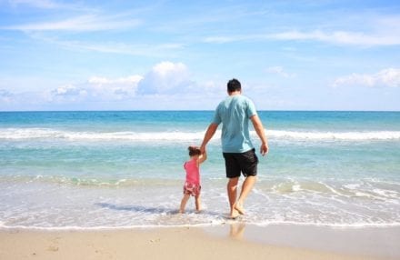 father and kid walking on the beach holding hands